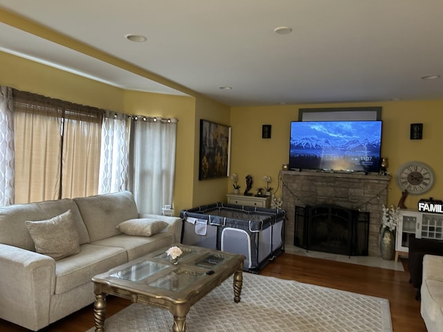 living room with a stone fireplace and hardwood / wood-style floors