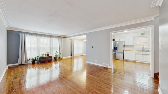 living room with light hardwood / wood-style flooring, ornamental molding, and sink