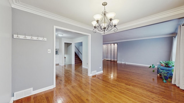 unfurnished dining area featuring a chandelier, ornamental molding, and hardwood / wood-style flooring