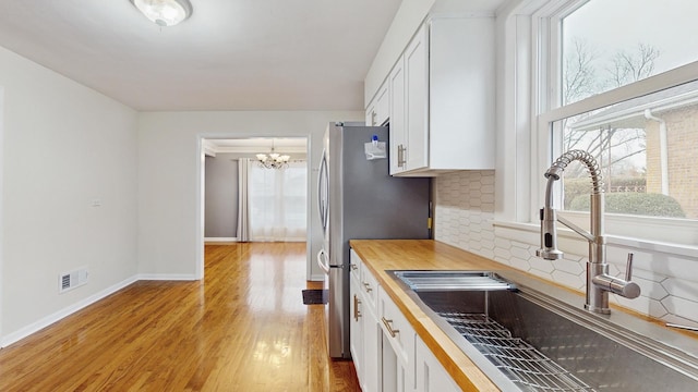 kitchen featuring white cabinetry, sink, tasteful backsplash, a chandelier, and light wood-type flooring