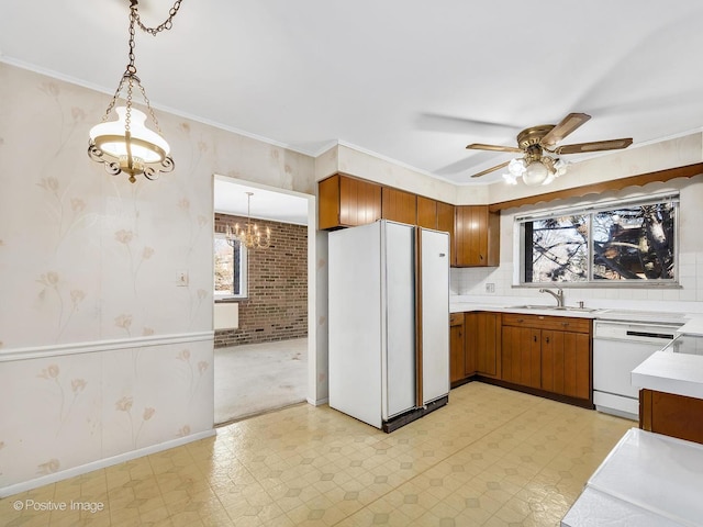 kitchen featuring white appliances, brick wall, sink, and hanging light fixtures