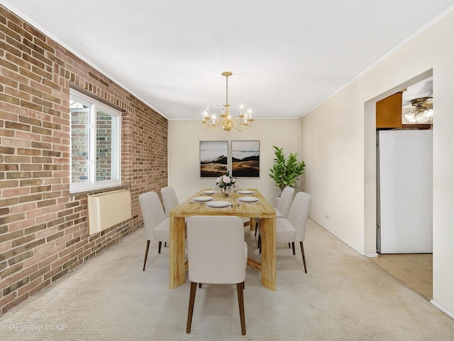 carpeted dining room with ornamental molding, brick wall, and a chandelier