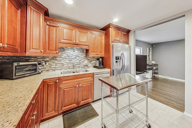 kitchen with backsplash, sink, light tile patterned flooring, light stone counters, and stainless steel appliances