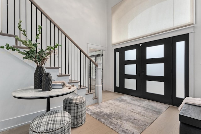 foyer with french doors, a towering ceiling, and light hardwood / wood-style floors