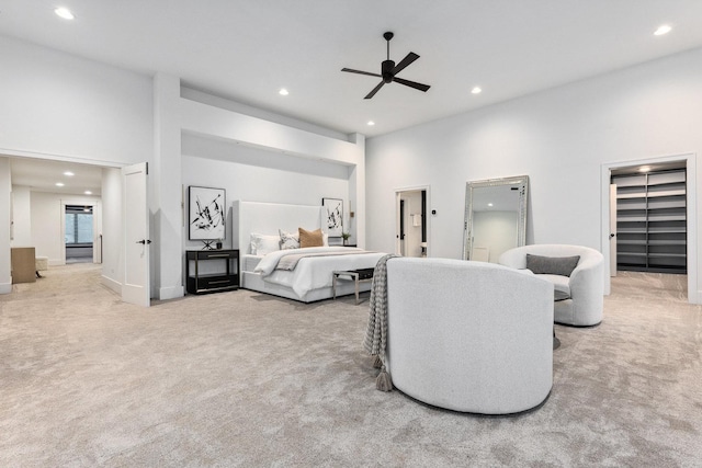 carpeted bedroom with ceiling fan, ensuite bathroom, and a high ceiling