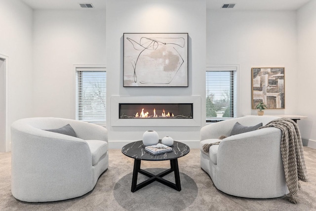 carpeted living room with plenty of natural light and a towering ceiling