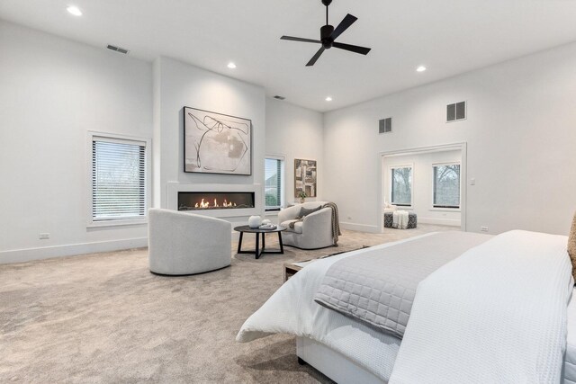 carpeted bedroom with multiple windows, a towering ceiling, and ceiling fan