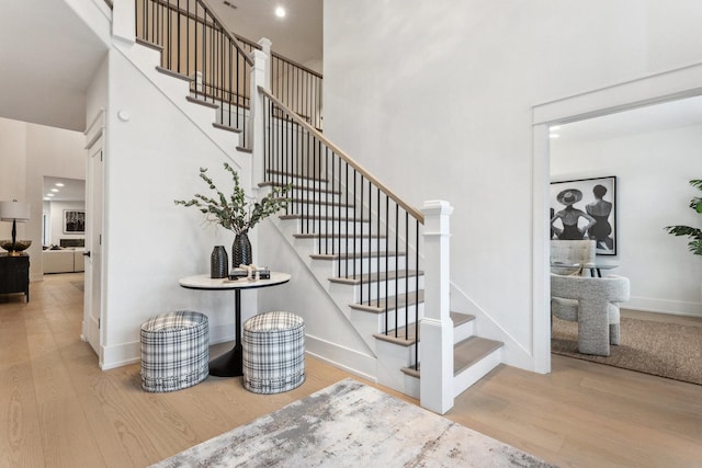 staircase featuring a towering ceiling and hardwood / wood-style flooring