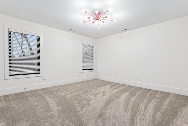 carpeted spare room with a notable chandelier