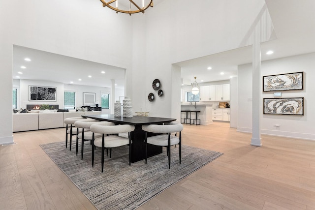 dining space with a towering ceiling and light hardwood / wood-style floors