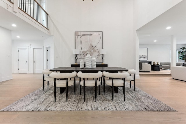 dining space with a high ceiling and light hardwood / wood-style floors