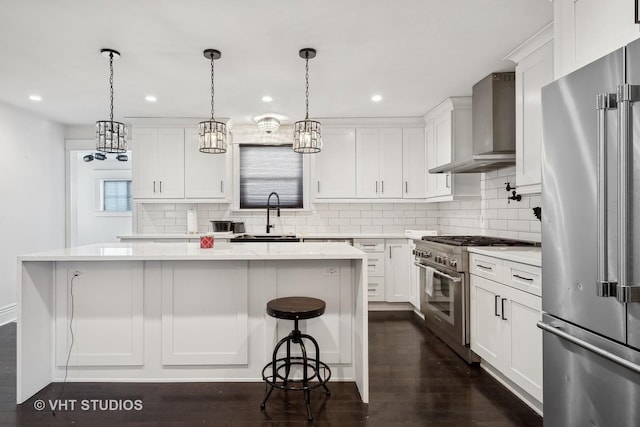 kitchen with white cabinets, high end appliances, and wall chimney exhaust hood