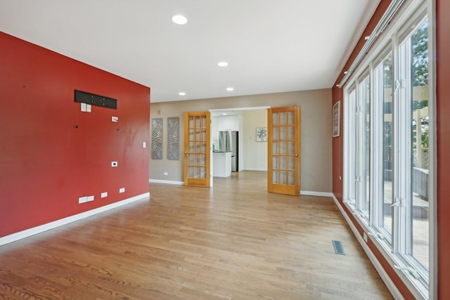 spare room featuring french doors and light hardwood / wood-style floors