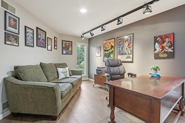 office area with light hardwood / wood-style floors and rail lighting