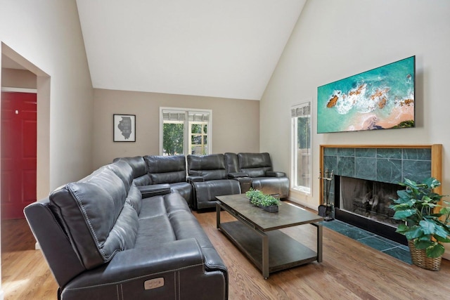 living room with high vaulted ceiling, a fireplace, and hardwood / wood-style flooring