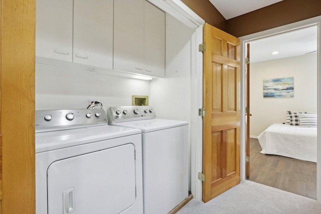 clothes washing area with cabinets, separate washer and dryer, and light carpet