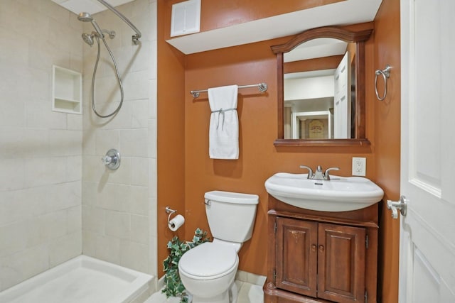 bathroom featuring tiled shower, vanity, and toilet