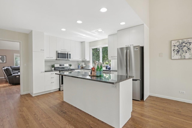 kitchen with white cabinetry, appliances with stainless steel finishes, a center island, light hardwood / wood-style flooring, and backsplash