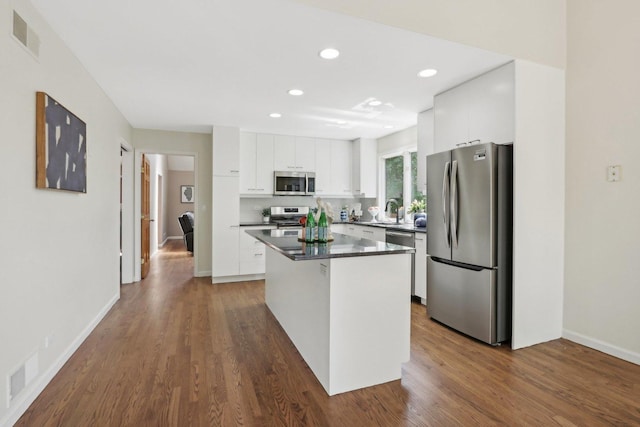 kitchen featuring white cabinets, stainless steel appliances, dark hardwood / wood-style flooring, and a center island