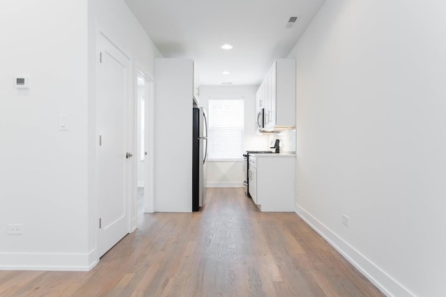 corridor with light wood-style floors, recessed lighting, visible vents, and baseboards