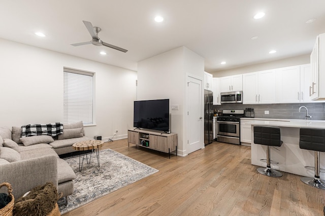 living area featuring baseboards, recessed lighting, a ceiling fan, and light wood-style floors