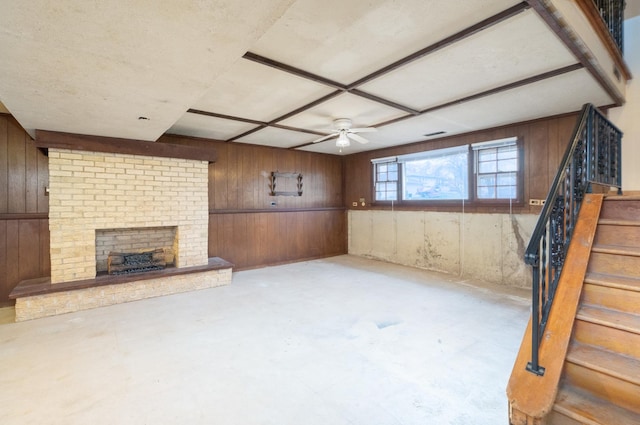 basement with a fireplace, ceiling fan, and wood walls