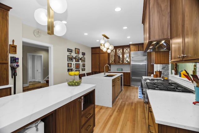 kitchen featuring tasteful backsplash, sink, hanging light fixtures, stainless steel appliances, and a center island with sink