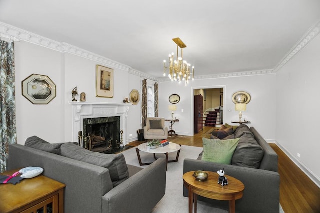 living room with hardwood / wood-style floors, a high end fireplace, ornamental molding, and a chandelier