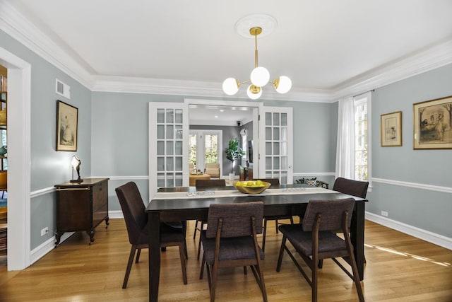 dining room featuring hardwood / wood-style floors, crown molding, a wealth of natural light, and french doors