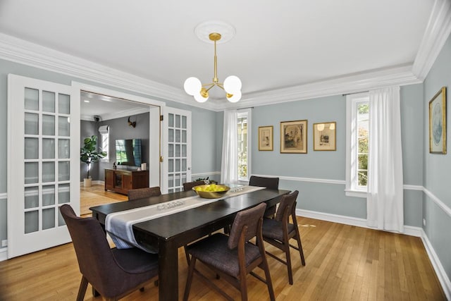 dining space featuring crown molding, an inviting chandelier, light hardwood / wood-style floors, and french doors