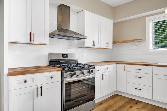 kitchen featuring wooden counters, stainless steel gas stove, and wall chimney exhaust hood