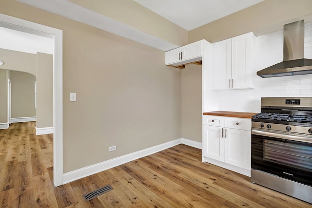 kitchen featuring gas stove, tasteful backsplash, white cabinetry, and wall chimney exhaust hood