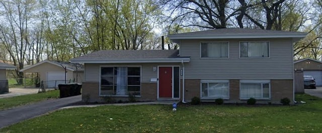 tri-level home with a garage, a front lawn, and an outdoor structure