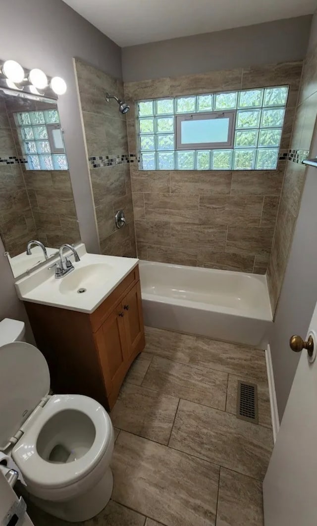 full bathroom with plenty of natural light, vanity, tiled shower / bath combo, and toilet