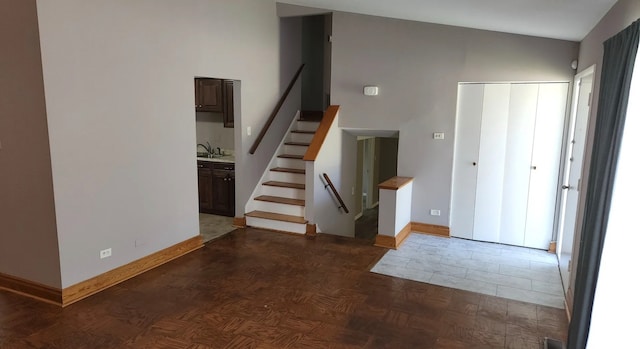 entryway with dark parquet flooring, sink, and vaulted ceiling