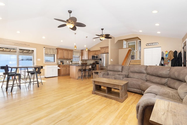 living room featuring ceiling fan, vaulted ceiling, and light hardwood / wood-style floors