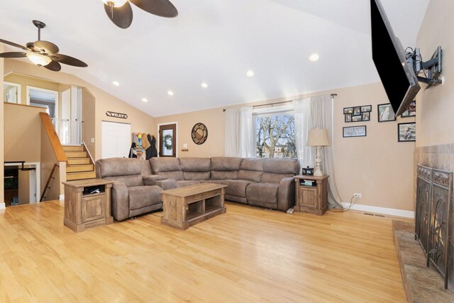 living room with light hardwood / wood-style floors, ceiling fan, and vaulted ceiling