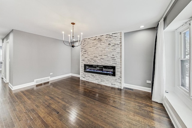 unfurnished living room featuring a chandelier, a large fireplace, and dark wood-type flooring