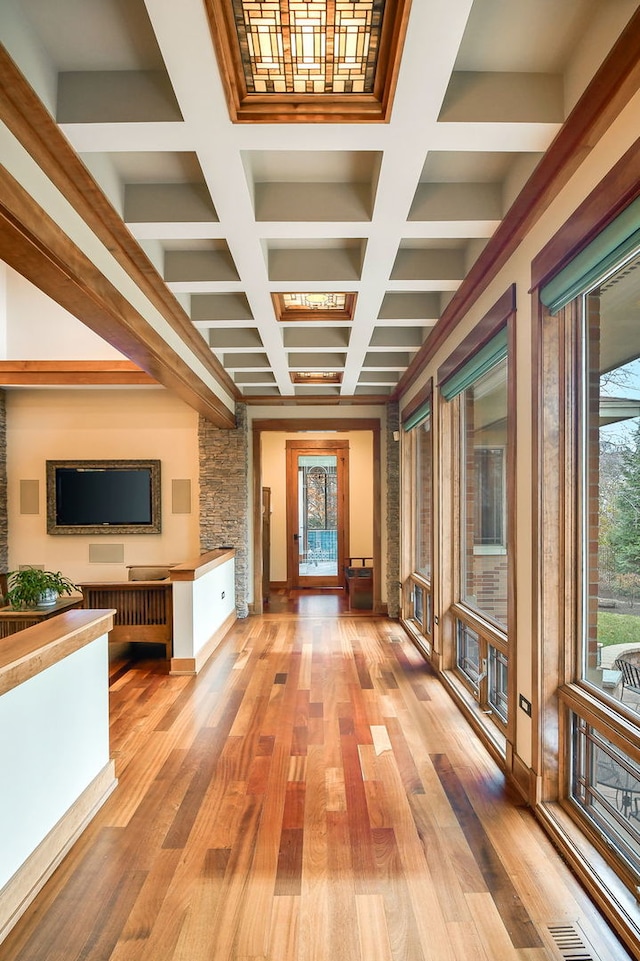 hallway with coffered ceiling, beam ceiling, and light wood-type flooring