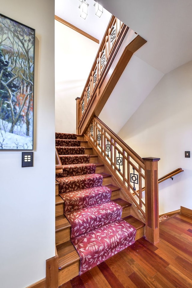 staircase featuring wood-type flooring and vaulted ceiling