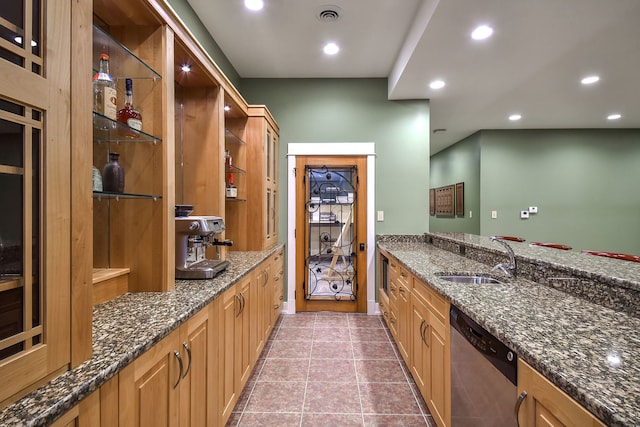 kitchen featuring stainless steel dishwasher, light tile patterned floors, sink, and dark stone countertops