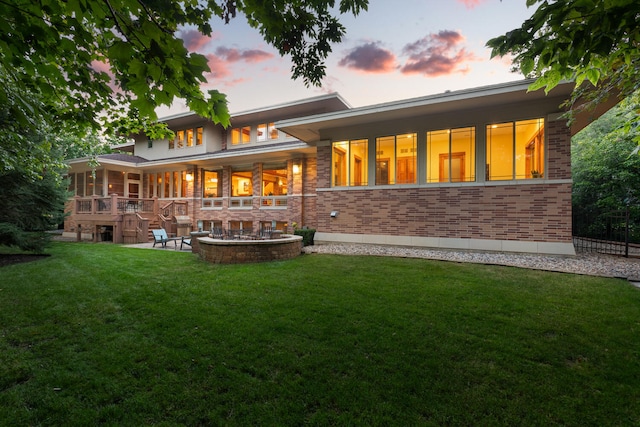 back house at dusk featuring a patio area and a lawn