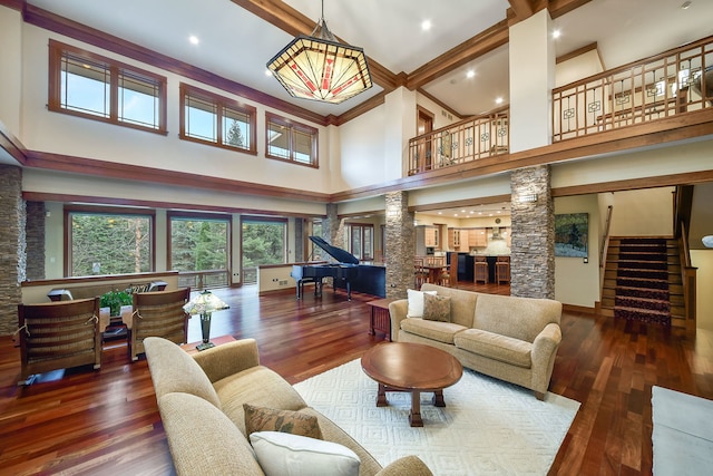 living room with dark hardwood / wood-style flooring, ornate columns, and a high ceiling