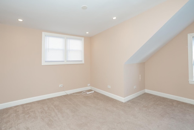 additional living space featuring light colored carpet and lofted ceiling