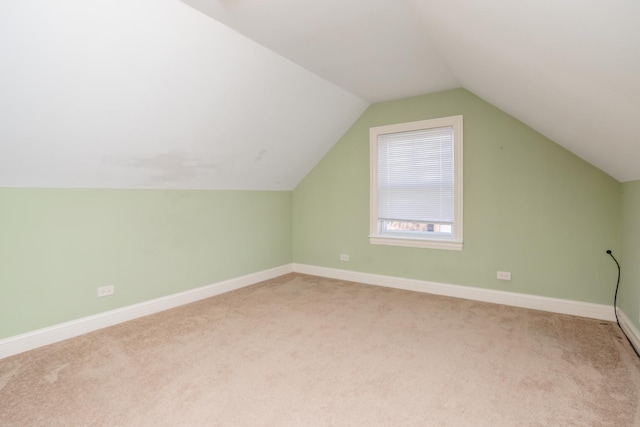 bonus room with lofted ceiling and light carpet