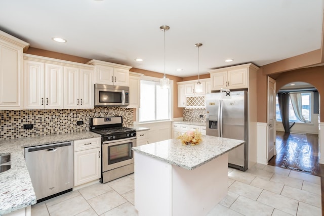 kitchen featuring decorative backsplash, light tile patterned floors, decorative light fixtures, light stone counters, and stainless steel appliances