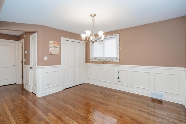 unfurnished dining area featuring a notable chandelier and wood-type flooring