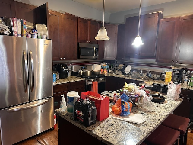 kitchen with light stone countertops, appliances with stainless steel finishes, and hanging light fixtures