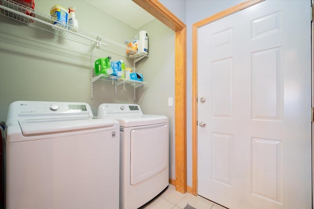 clothes washing area with washing machine and clothes dryer and light tile patterned floors