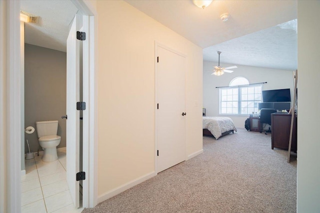 carpeted bedroom with ceiling fan, vaulted ceiling, ensuite bath, and a textured ceiling